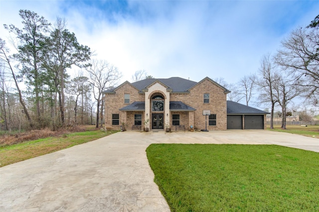 traditional home with driveway, a garage, a front lawn, and brick siding