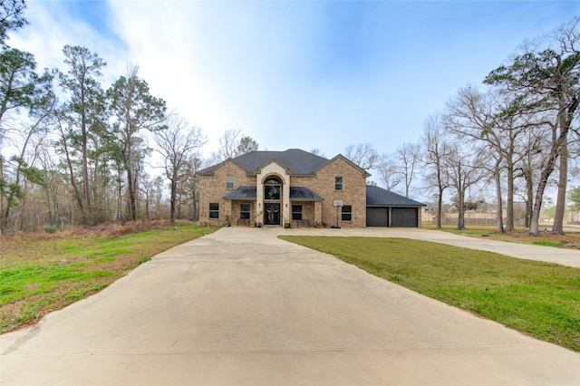 french provincial home featuring a garage, concrete driveway, a front lawn, and brick siding