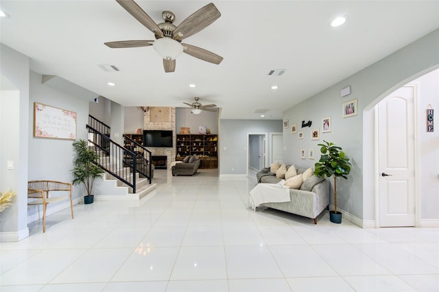 living area with arched walkways, recessed lighting, a large fireplace, light tile patterned flooring, and stairs