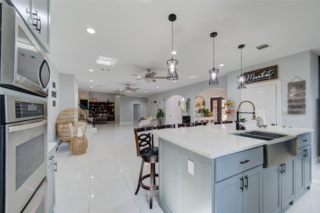 kitchen with arched walkways, light countertops, visible vents, appliances with stainless steel finishes, and a sink