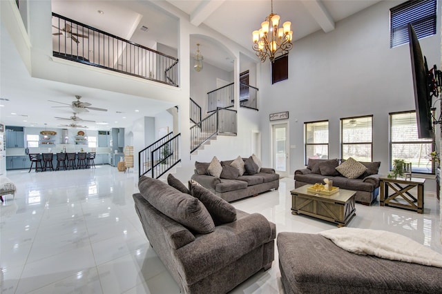 living room featuring stairs, ceiling fan with notable chandelier, plenty of natural light, and beam ceiling