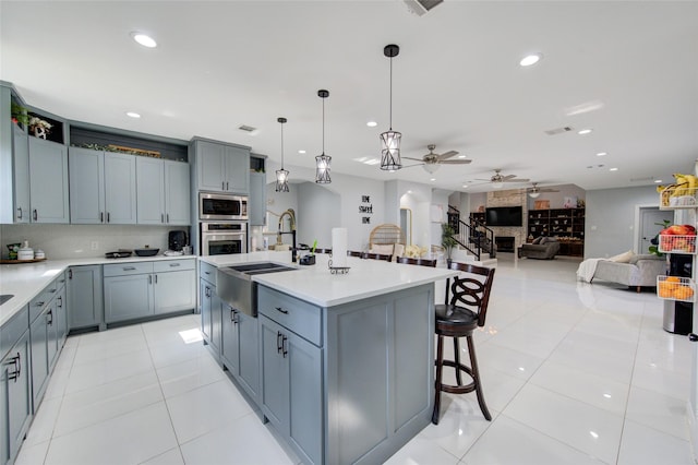 kitchen with a breakfast bar, light tile patterned floors, stainless steel appliances, light countertops, and a sink