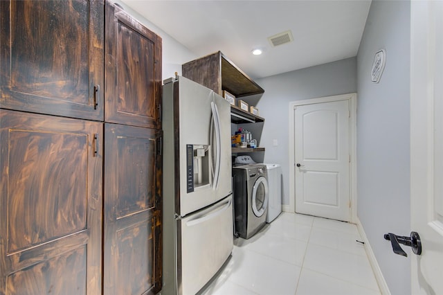 laundry room featuring washing machine and clothes dryer, light tile patterned floors, visible vents, laundry area, and baseboards