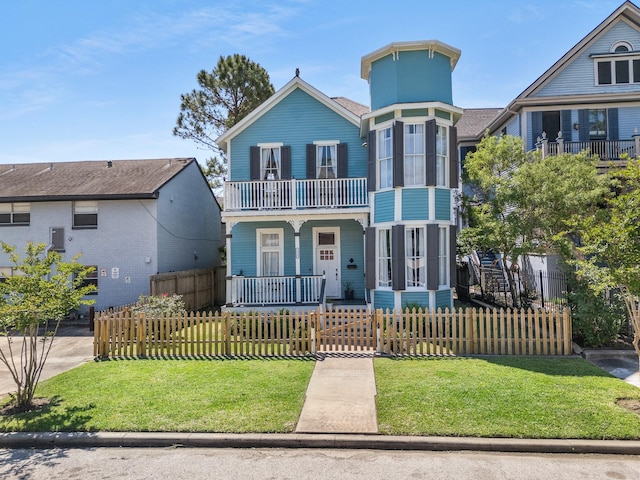 view of front of home featuring covered porch, a fenced front yard, a front yard, and a balcony