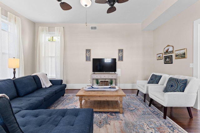 living room featuring baseboards, ceiling fan, visible vents, and wood finished floors