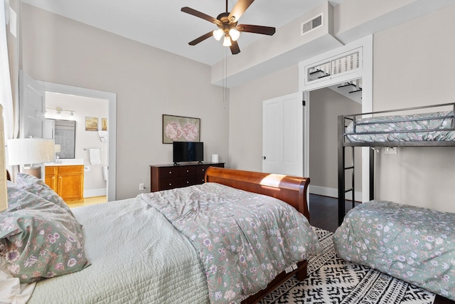 bedroom with ceiling fan, ensuite bathroom, wood finished floors, visible vents, and baseboards