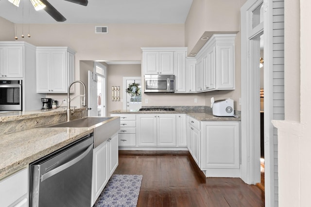 kitchen with visible vents, dark wood finished floors, light stone counters, stainless steel appliances, and white cabinetry