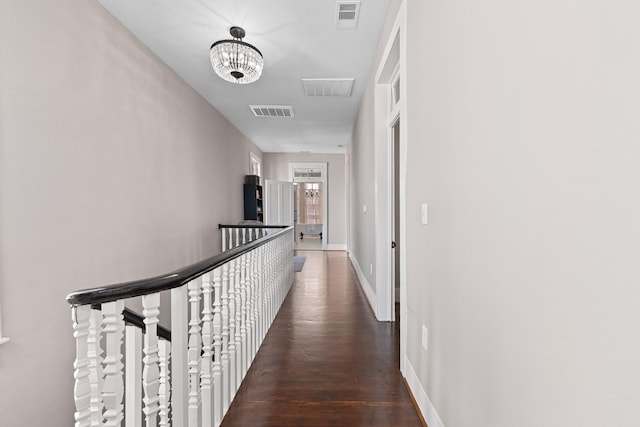 hall with an upstairs landing, wood finished floors, visible vents, and baseboards