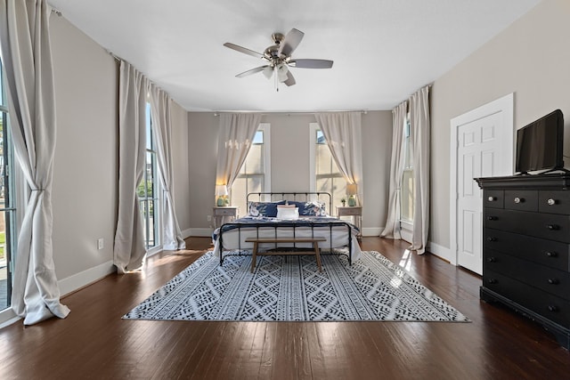 bedroom featuring a ceiling fan, multiple windows, baseboards, and hardwood / wood-style floors