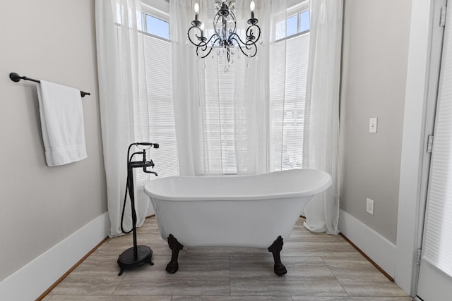 full bath with a soaking tub, plenty of natural light, baseboards, and wood finished floors