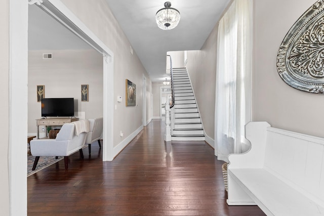 foyer with a chandelier, hardwood / wood-style flooring, visible vents, baseboards, and stairway