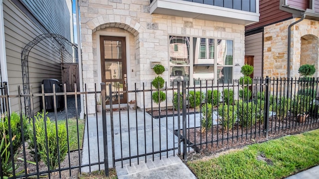 entrance to property with board and batten siding, stone siding, fence, and a gate