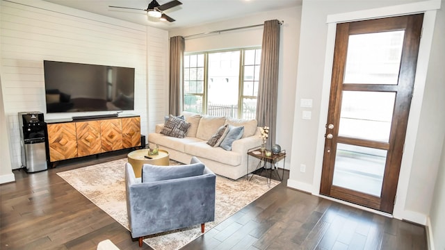 living room with ceiling fan, baseboards, and dark wood-style flooring