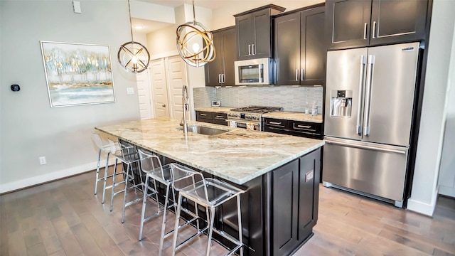 kitchen with light stone counters, a breakfast bar area, a sink, backsplash, and high end appliances