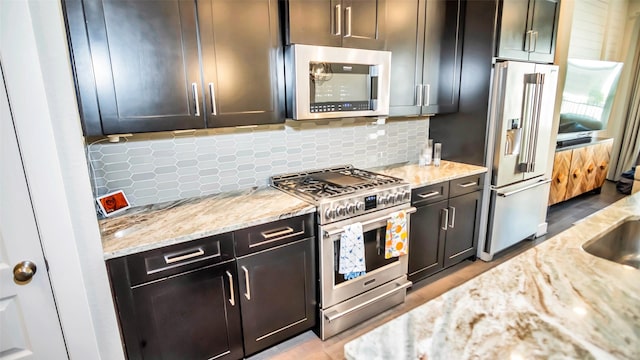 kitchen with stainless steel appliances, backsplash, and light stone counters