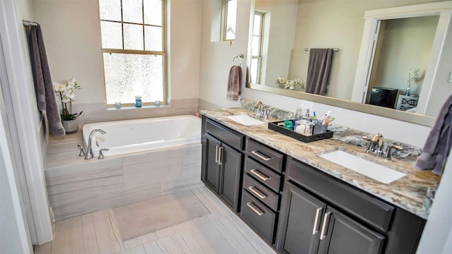 bathroom with double vanity, a sink, and a bath