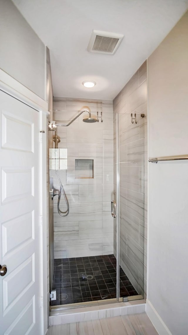 bathroom with a shower stall and visible vents