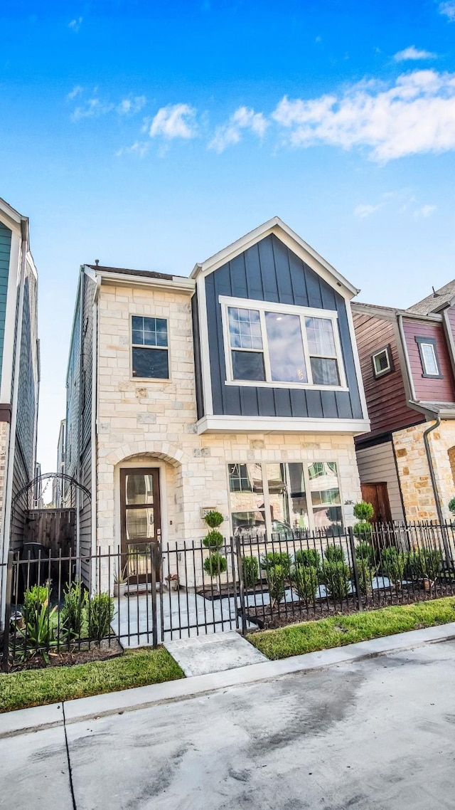 multi unit property with stone siding, board and batten siding, and a fenced front yard