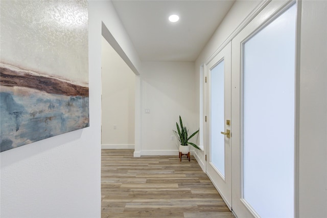 corridor with light wood-type flooring, baseboards, and recessed lighting