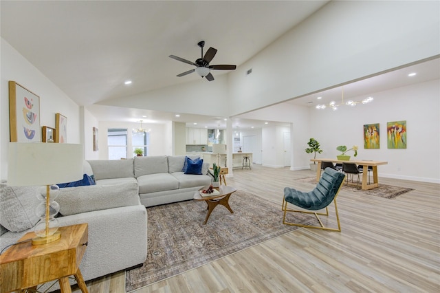 living room with light wood finished floors, recessed lighting, high vaulted ceiling, baseboards, and ceiling fan with notable chandelier