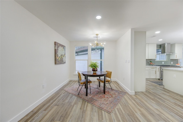 dining room with light wood-style floors, baseboards, and a notable chandelier