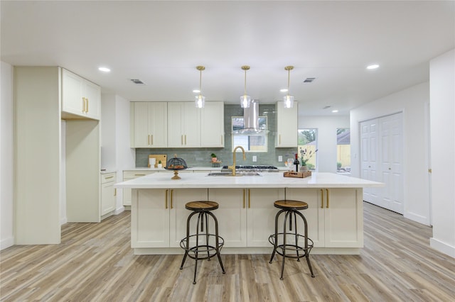 kitchen featuring light wood-type flooring, island exhaust hood, visible vents, and white cabinetry