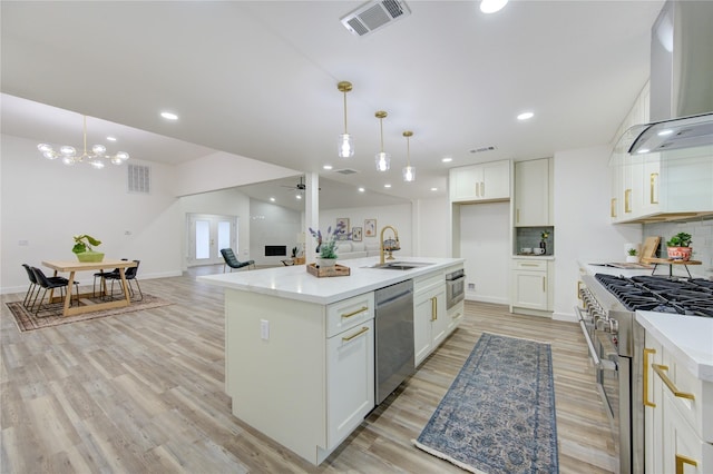 kitchen with stainless steel appliances, a sink, visible vents, wall chimney range hood, and backsplash