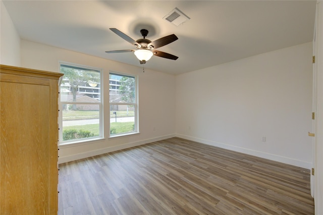 spare room featuring baseboards, plenty of natural light, visible vents, and wood finished floors