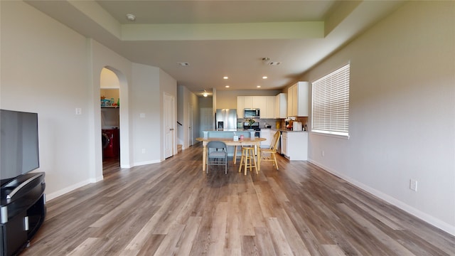 dining room with light wood-style floors, arched walkways, baseboards, and recessed lighting