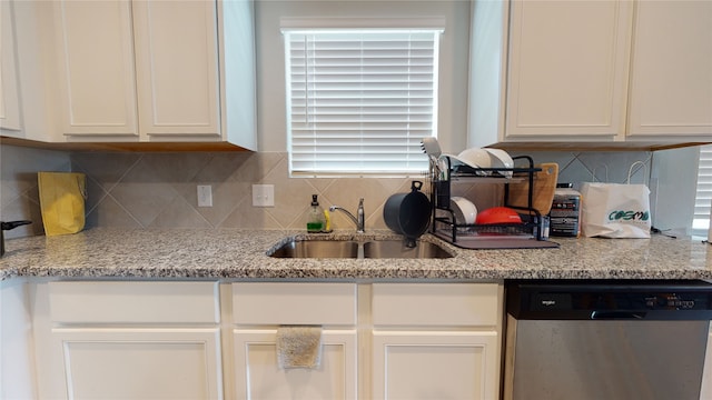 kitchen featuring light stone counters, a sink, white cabinetry, decorative backsplash, and dishwasher