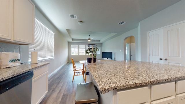 kitchen featuring visible vents, arched walkways, dishwasher, light wood-style flooring, and a tray ceiling