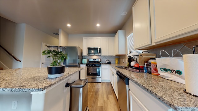 kitchen featuring light wood finished floors, stainless steel appliances, visible vents, backsplash, and white cabinets