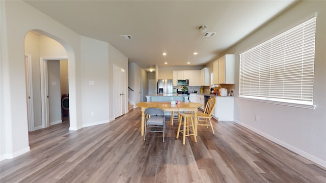 dining room with arched walkways, visible vents, and wood finished floors