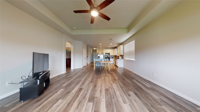 unfurnished living room with baseboards, arched walkways, ceiling fan, light wood-style floors, and recessed lighting