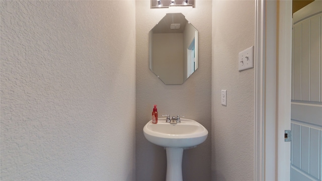 bathroom featuring a textured wall and a sink