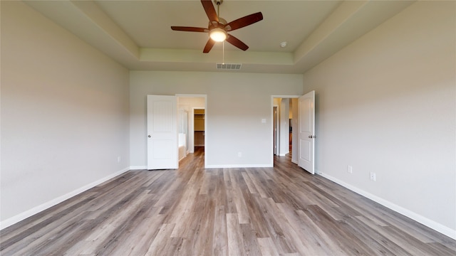 unfurnished bedroom with visible vents, baseboards, a raised ceiling, and wood finished floors