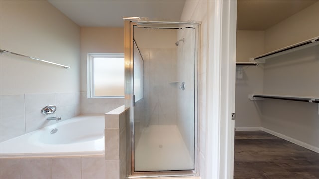 bathroom featuring a stall shower, a garden tub, baseboards, and a walk in closet