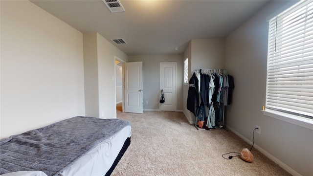 bedroom with light colored carpet, visible vents, baseboards, and multiple windows