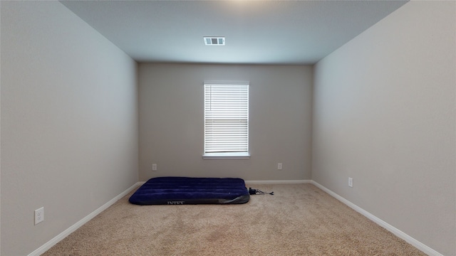 carpeted empty room with visible vents and baseboards