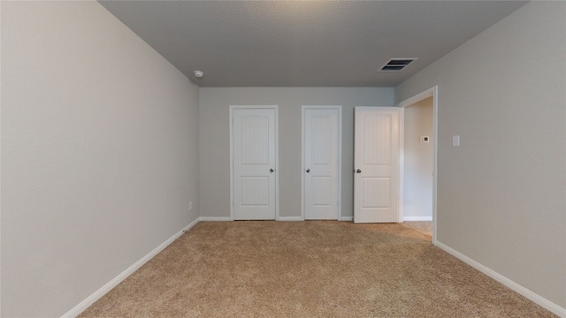 unfurnished bedroom featuring light carpet, visible vents, and baseboards