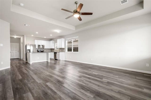 24902 Bastiani Canvas Ln, Katy, TX 77493 - unfurnished living room featuring recessed lighting, ceiling fan, dark wood finished floors, baseboards, and a tray ceiling
