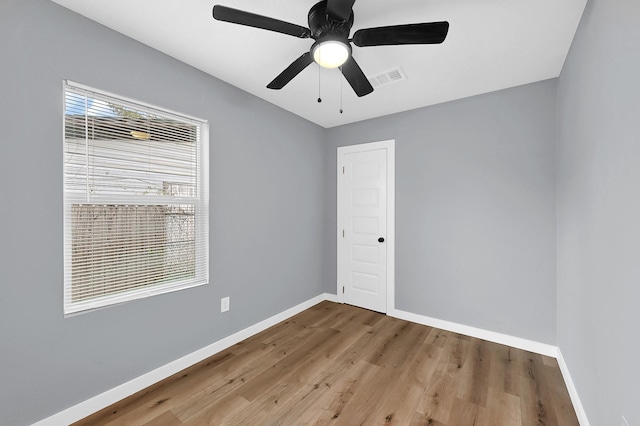 empty room with a ceiling fan, visible vents, baseboards, and wood finished floors