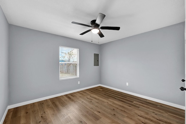 unfurnished room with wood finished floors, electric panel, and baseboards