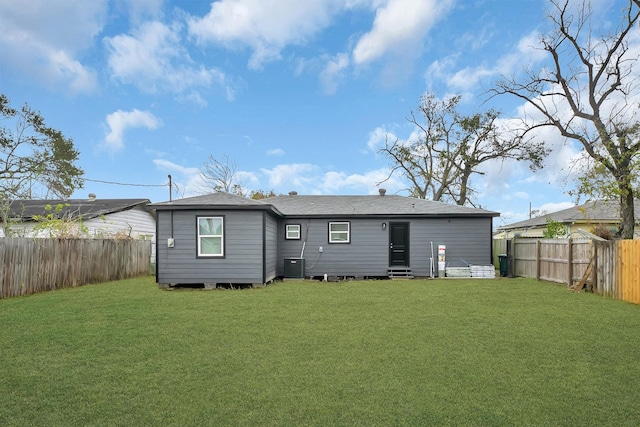 rear view of property featuring central AC, a yard, a fenced backyard, and roof with shingles