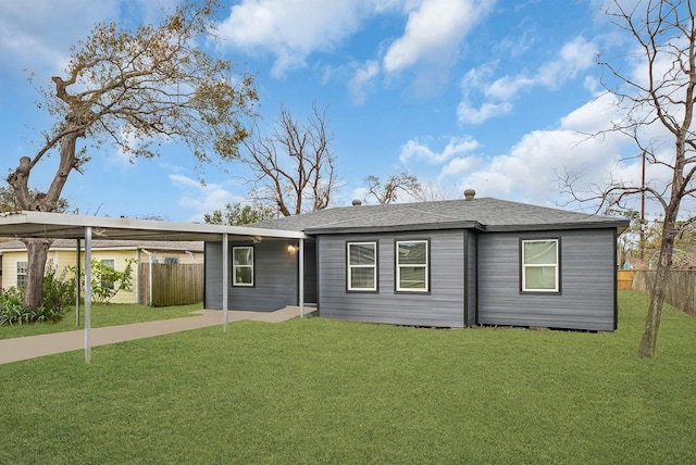 single story home featuring a shingled roof, fence, an attached carport, and a front yard