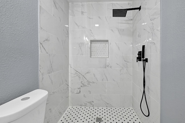 bathroom featuring toilet, a shower stall, and a textured wall