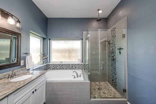 bathroom featuring a stall shower, a bath, and vanity