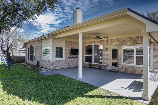 rear view of property with brick siding, a lawn, a patio area, fence, and ceiling fan