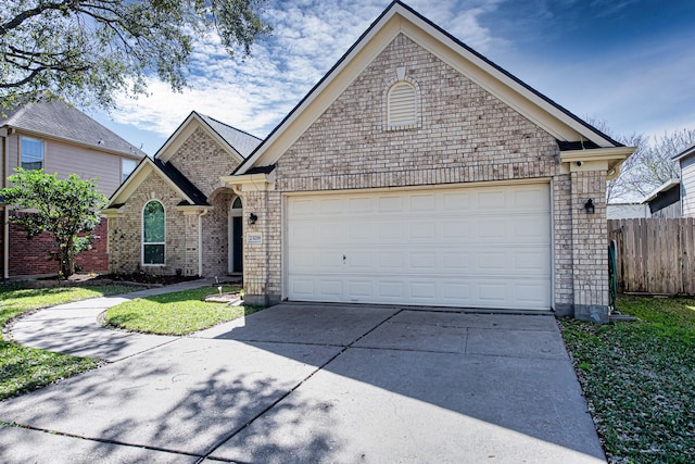 view of front of property with driveway, brick siding, an attached garage, and fence