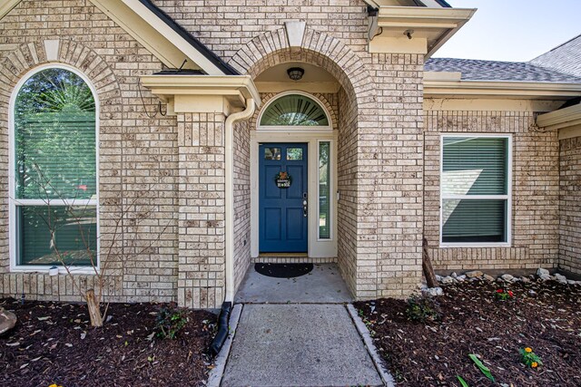 property entrance with brick siding and roof with shingles